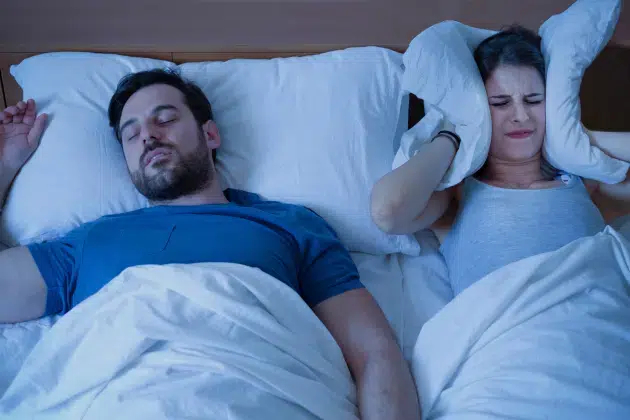 Couple in Cary, NC sleeping while husband snores due to sleep apnea, disturbing wife’s sleep