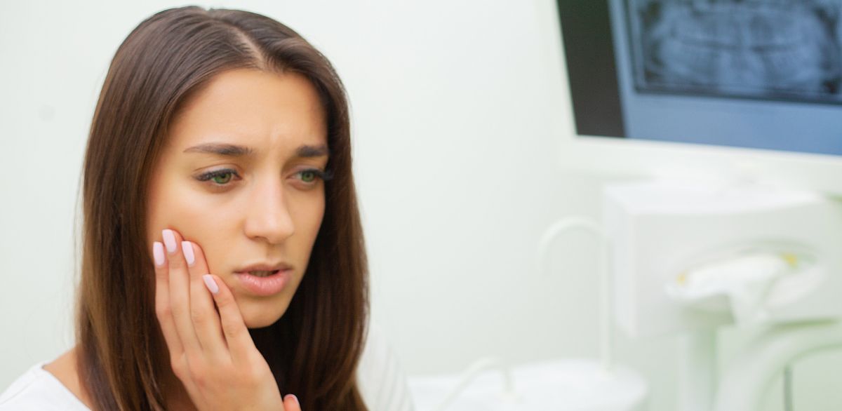 Female patient showing signs of tooth or gum pain at the dentist’s office