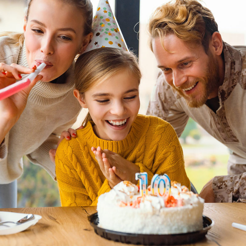 Beautiful happy family laughing while celebrating birthday of daughter at home