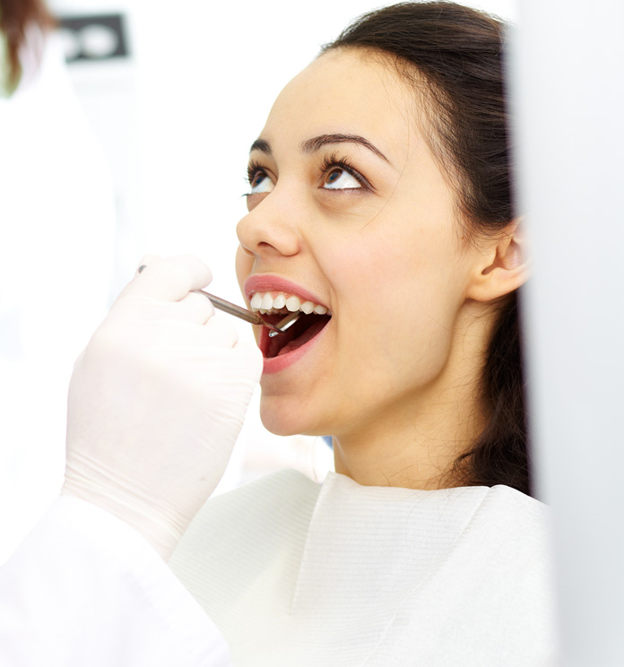 a dentist checking a woman's teeth as part of a deep cleaning procedure in alexandria