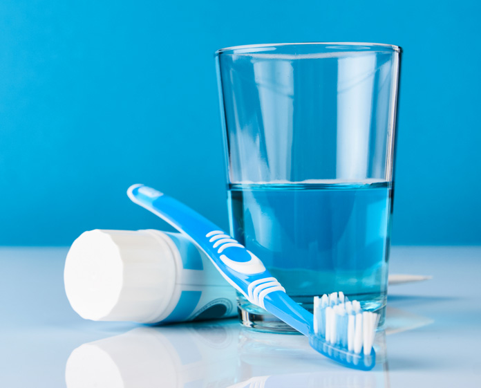 toothbrush, toothpaste, and fluoride mouthwash in a glass to protect teeth health