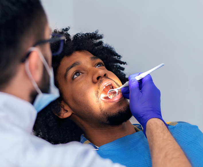 dentist performing oral cancer screening on patient in alexandria